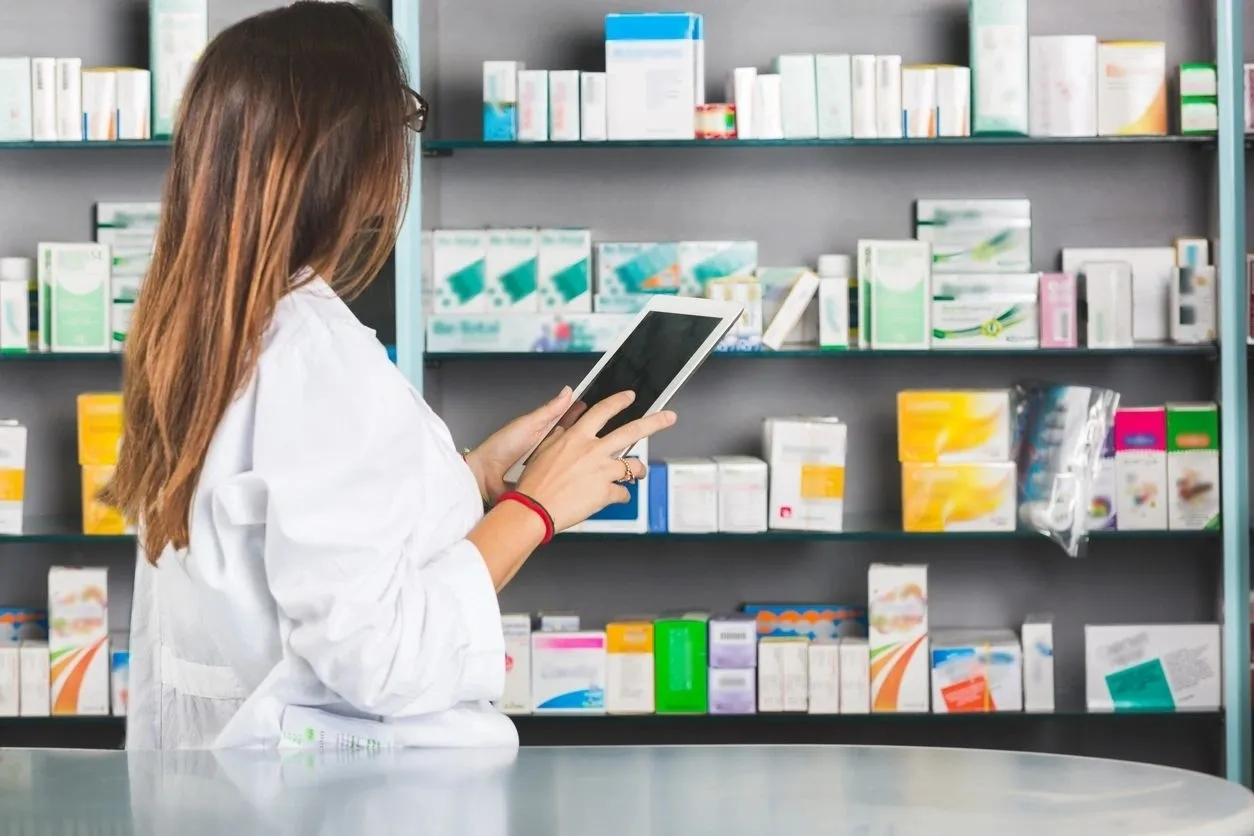 A woman is holding her tablet in front of the shelves.