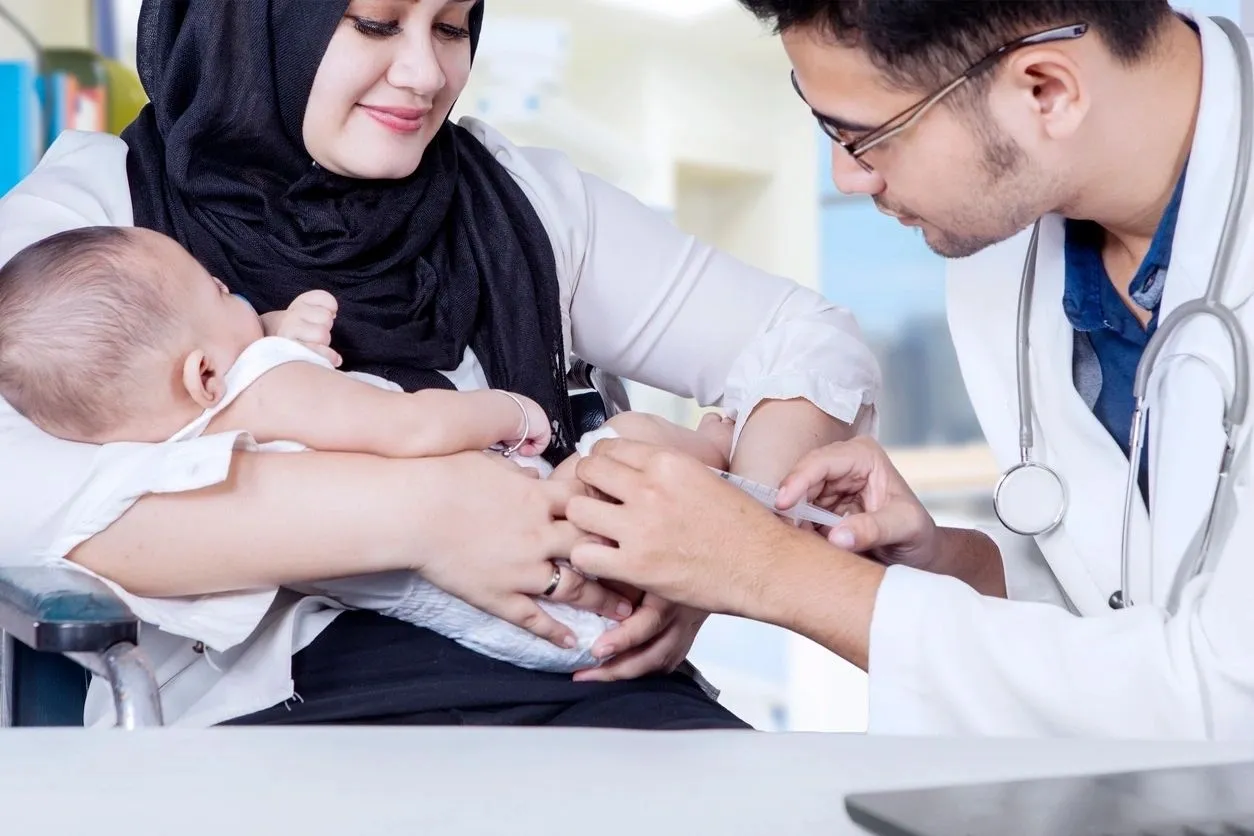 A doctor and nurse holding hands with a baby.